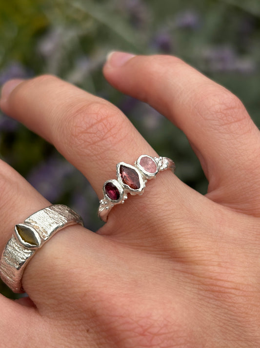 A pink tourmaline fairy inspired ring worn on a hand with a woodland background 